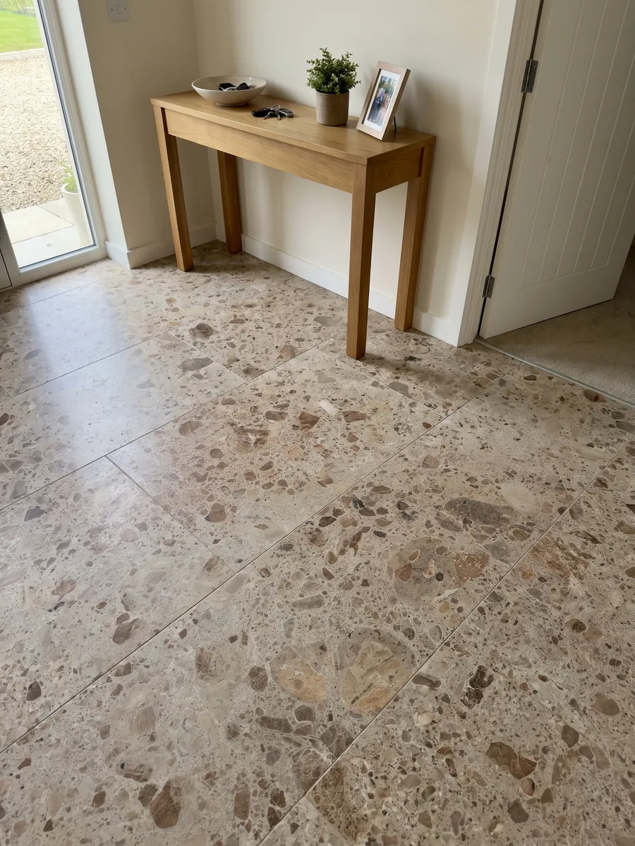 Entryway floor in large slabs of beige Ambrosia marble with natural light: beige matrix with rounded brown and rust fragments in several sizes