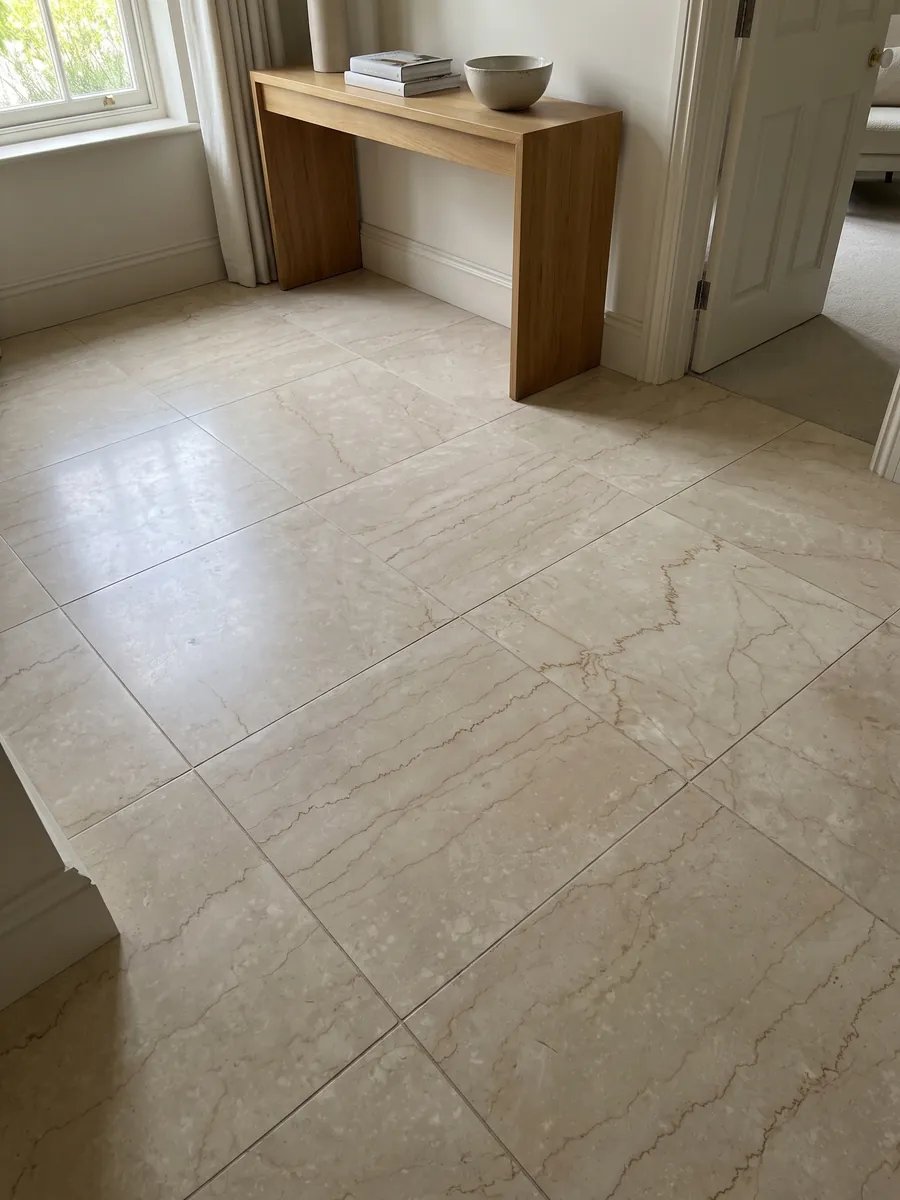 Entryway floor in large slabs of beige Botticino Classico marble with natural light: beige crossed horizontally by fine jagged light brown veins