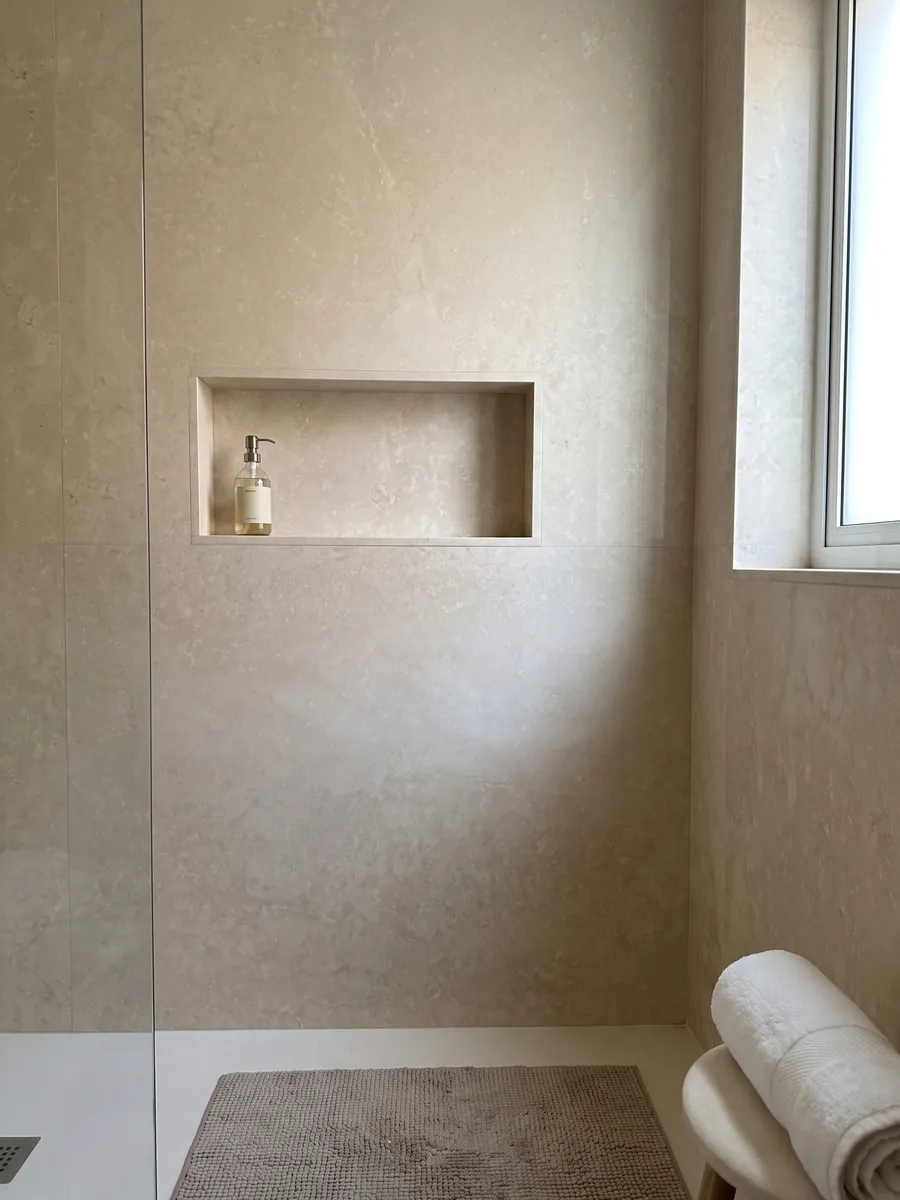 Shower clad in full slabs of Botticino Light beige marble with a recessed niche: very uniform light beige seen as a full slab