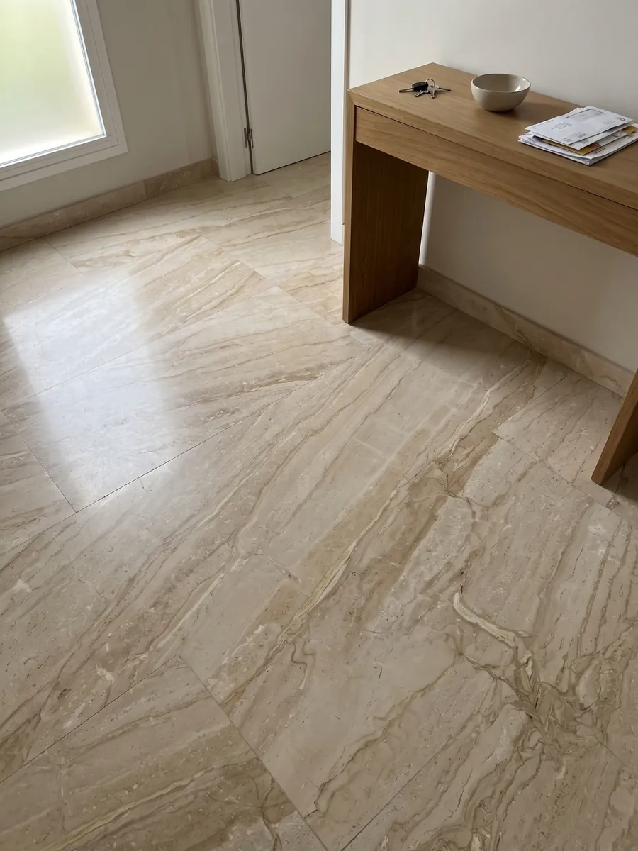 Entryway floor in large slabs of beige Breccia Sarda marble with natural light: warm beige with diagonal cream and light brown veins