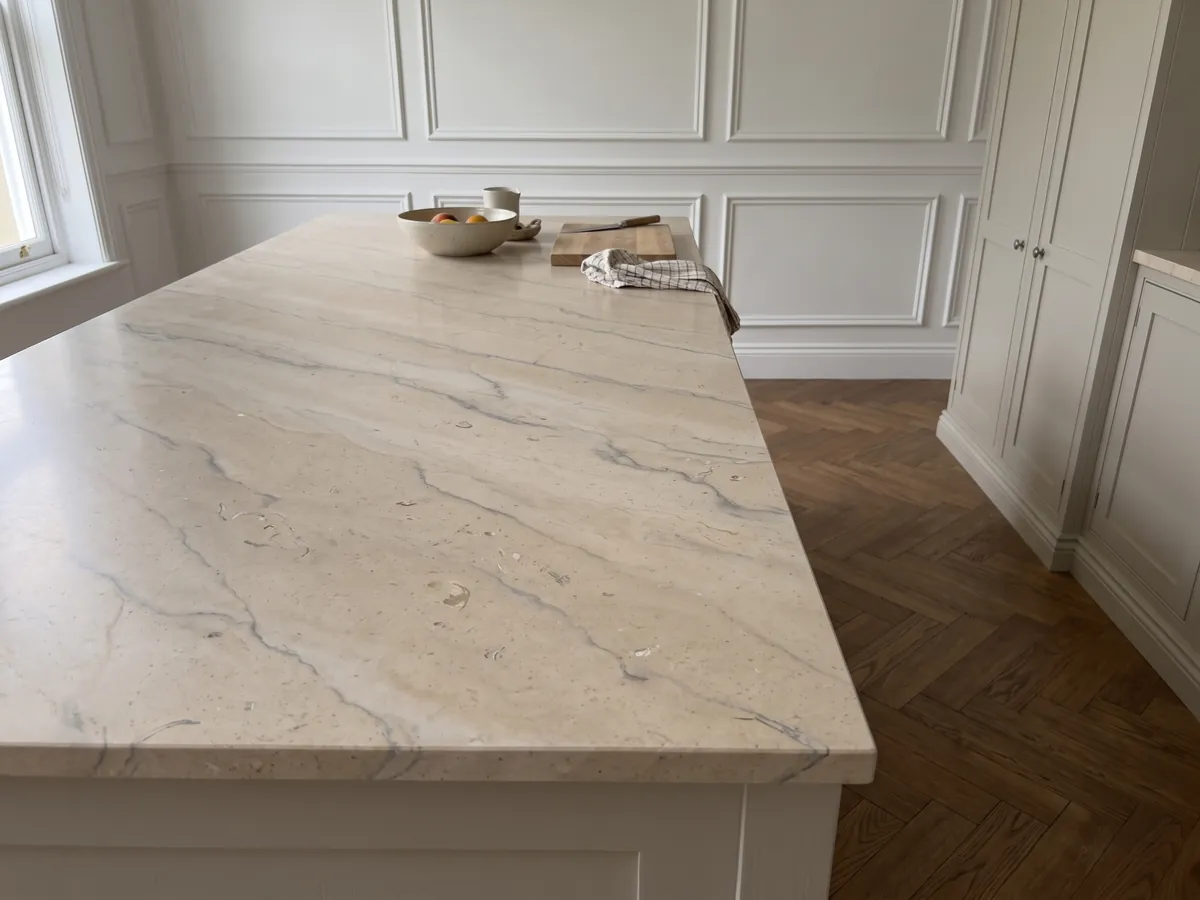 Kitchen island with a Beige Maya marble countertop and a straight edge in a kitchen with natural light: warm beige with soft gray veins and small fossils