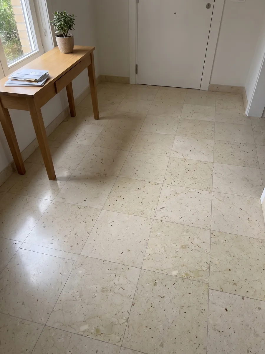Entryway floor in large beige Pietra Ducale marble slabs with natural light: yellowish cream with small fossil fragments and brown dots