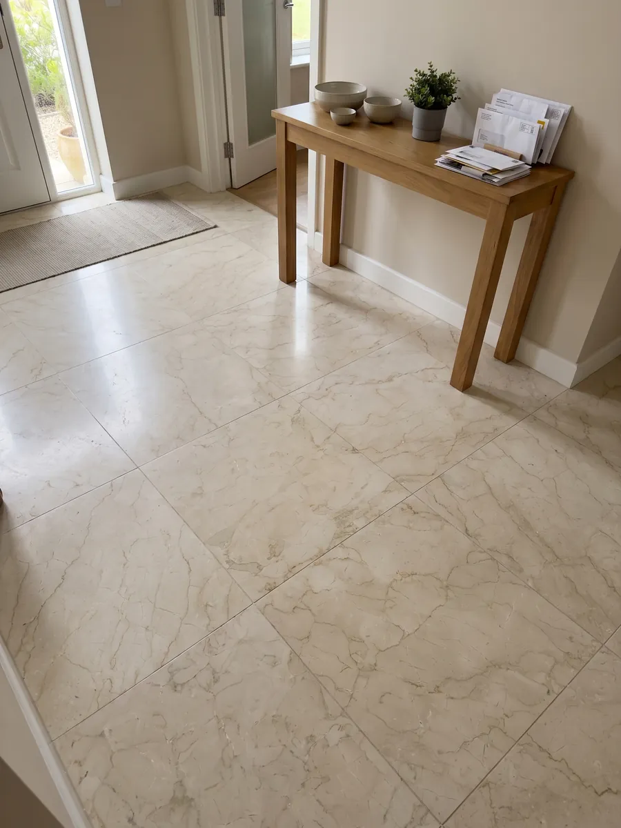 Entryway floor in large beige Pietra Orsera marble slabs with natural light: light cream with a web of very faint beige veins