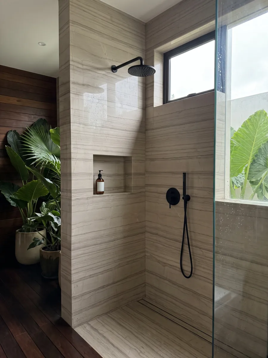 Shower clad in full slabs of beige Striato Elegante marble with a recessed niche: taupe beige with parallel horizontal lines that recall wood