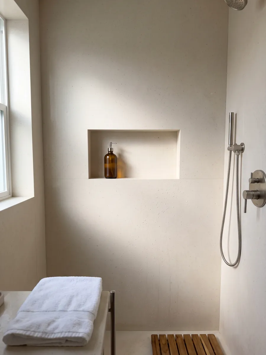 Shower clad in full beige Veselje marble slabs with a recessed niche: smooth, even cream with barely visible dark specks