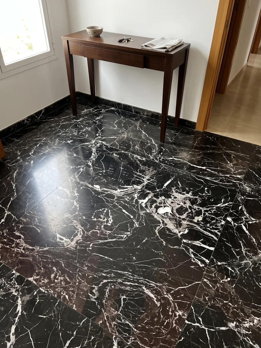 Entryway floor in large slabs of Black Rose marble with natural light: black with a dense web of white veins and a lower area with a brown tint