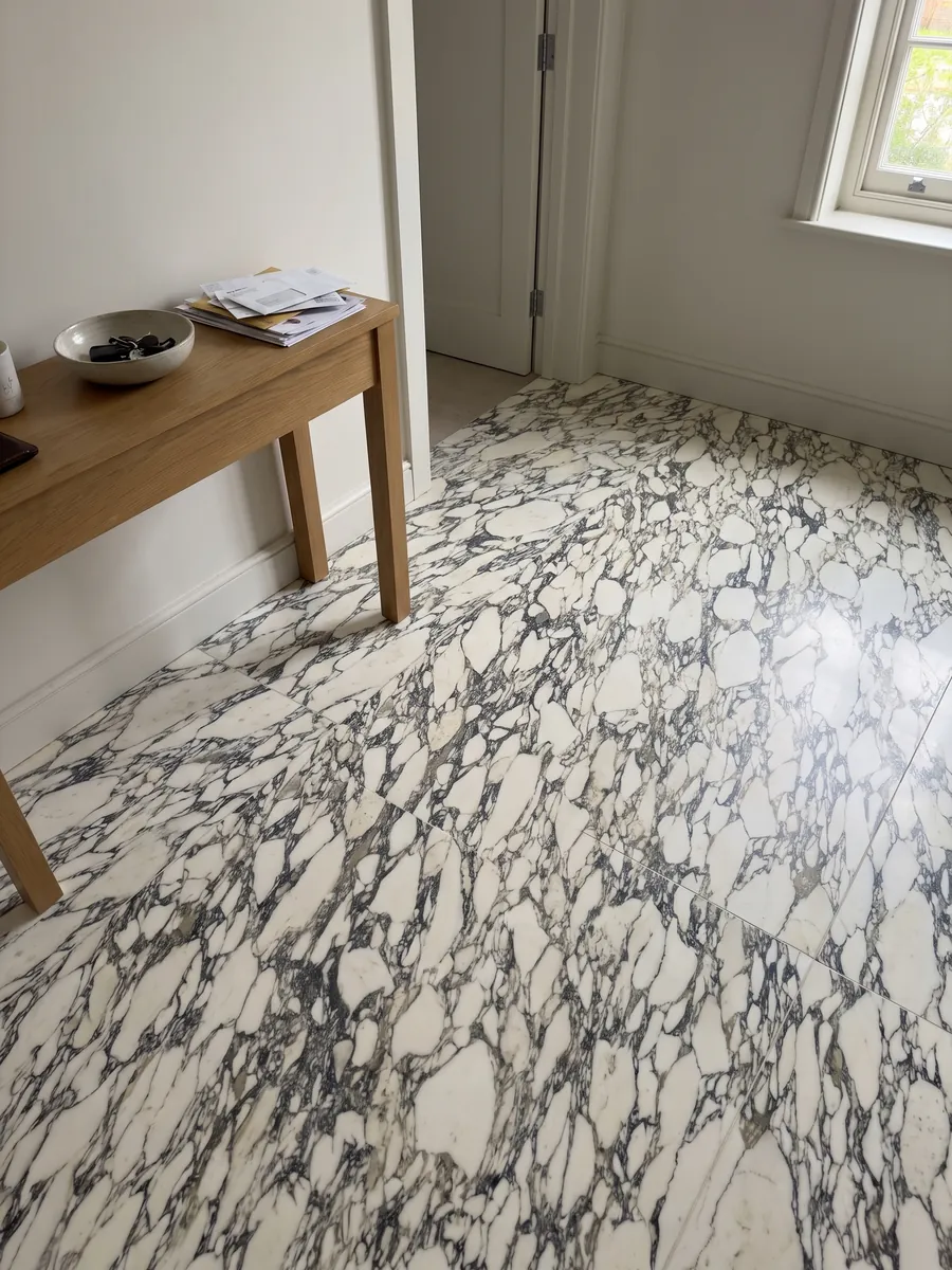 Entryway floor in large slabs of white Arabescato Corchia marble with natural light: a very dense web of fine dark veins enclosing many small white fragments