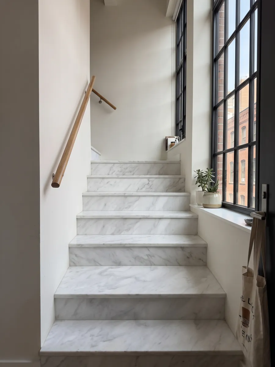 Interior staircase with Blanco Bego marble steps and a handrail: white with soft light gray veining