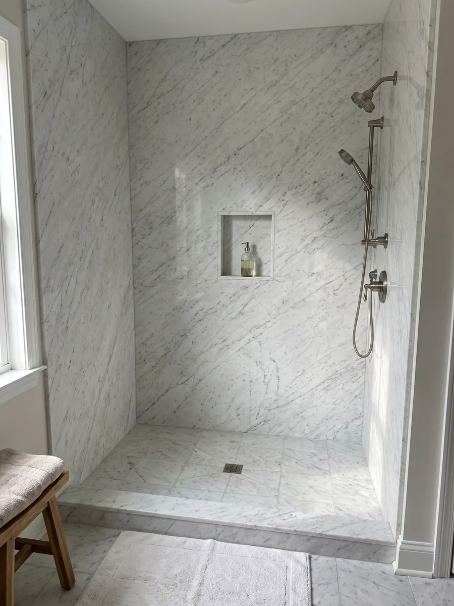 Shower clad in full slabs of white Bianco Carrara C Extra marble with a recessed niche: white with fine, soft gray veins running diagonally across the whole slab