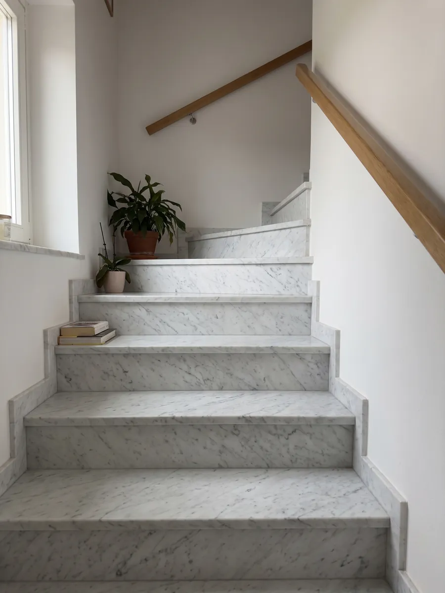 Interior staircase with white Bianco Carrara C Extra marble steps and a handrail: white with fine, soft gray veins running diagonally across the whole slab
