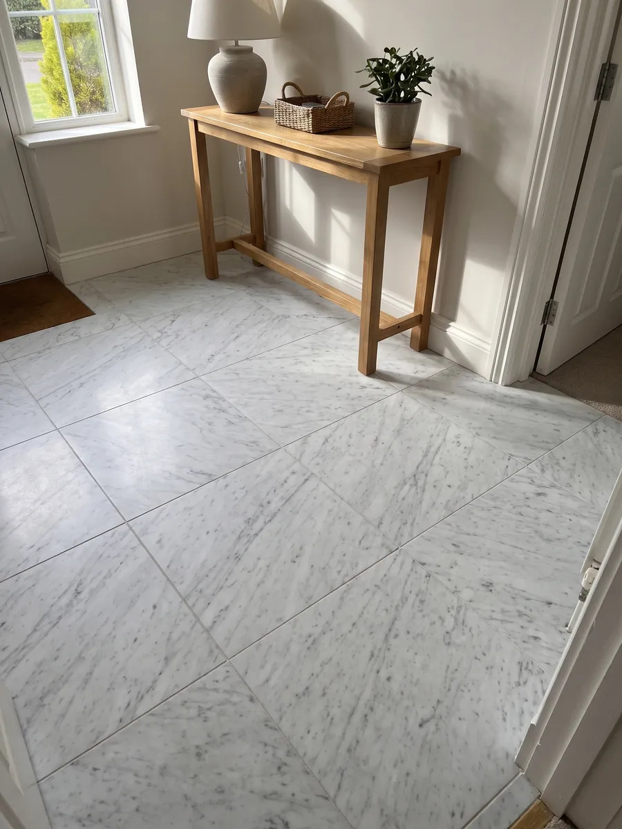 Entryway floor in large slabs of white Bianco Carrara C Extra marble with natural light: white with fine, soft gray veins running diagonally across the whole slab