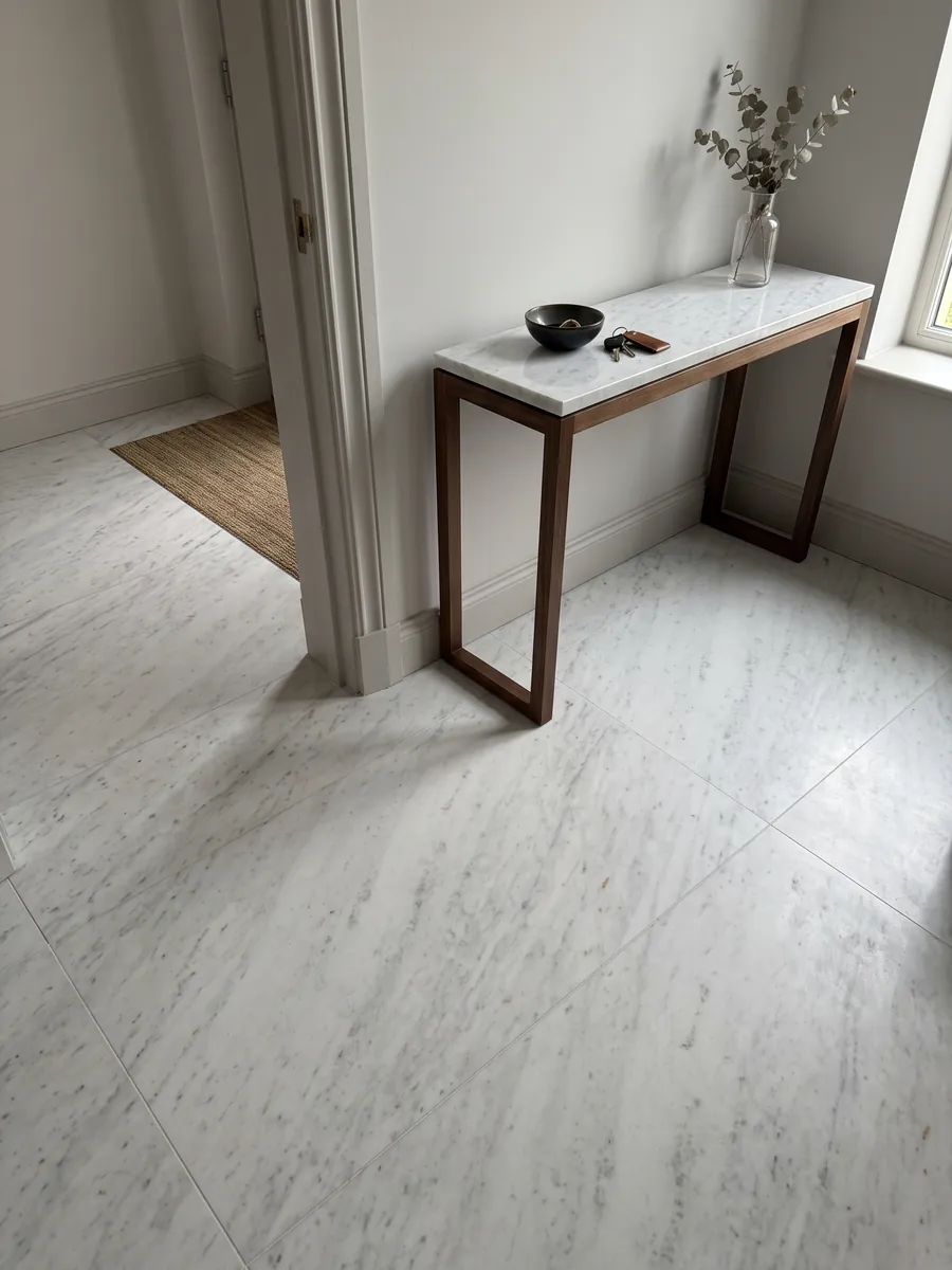 Entryway floor in large Bianco Brasile marble slabs with natural light: a cold, nearly plain white with faint gray lines on the diagonal