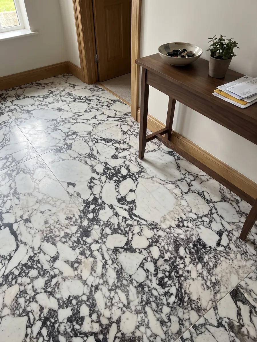Entryway floor in large slabs of white Breccia Capraia marble with natural light: white fragments surrounded by a dense dark gray web with violet tones