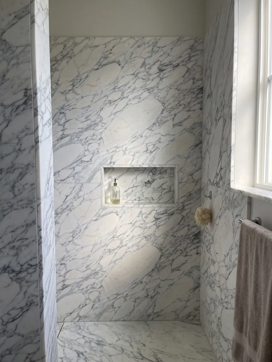 Shower clad in full slabs of white Breccia di Serravezza marble with a recessed niche: white fragments with a fine bluish gray web spread across the whole slab