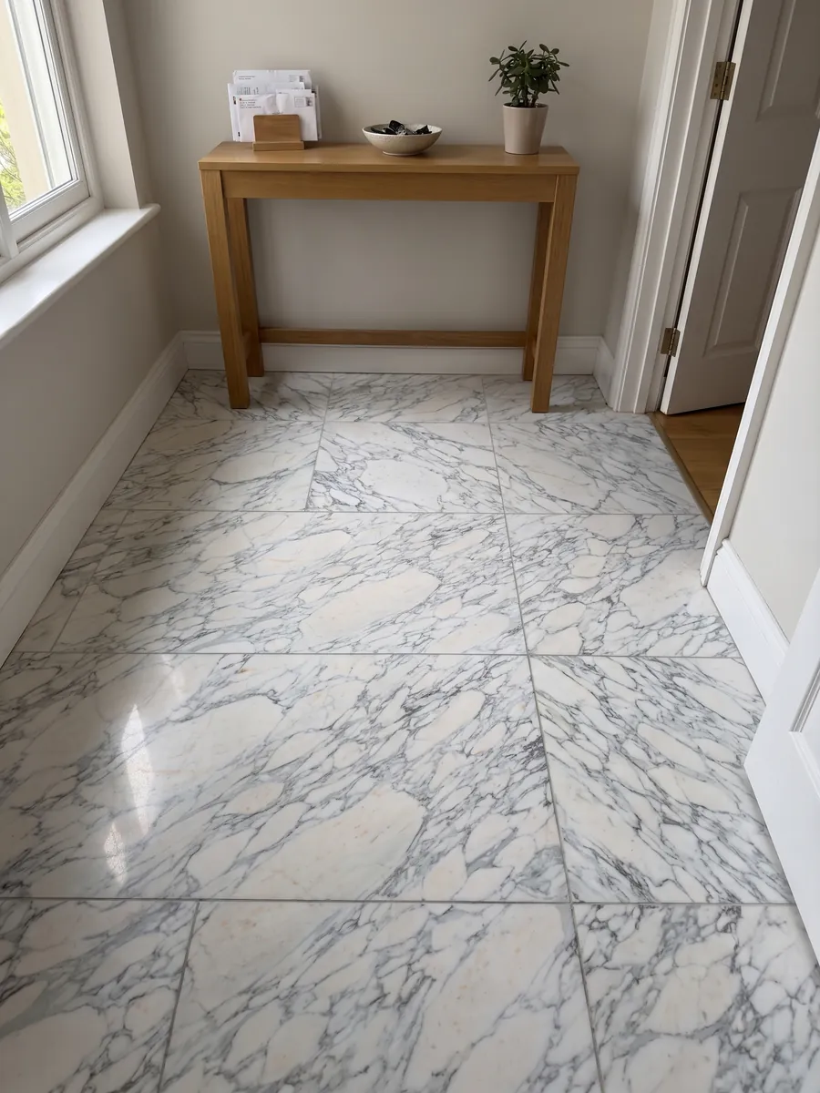 Entryway floor in large slabs of white Breccia di Serravezza marble in natural light: white fragments with a fine bluish gray web spread across the whole slab