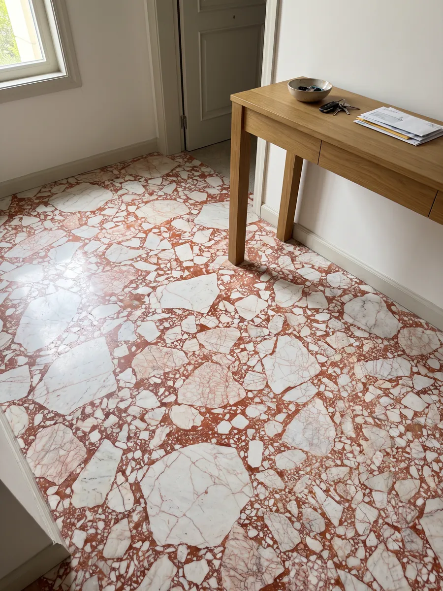 Entryway floor in large slabs of white Calacatta Antique marble with natural light: angular white fragments joined by an intense coral red matrix