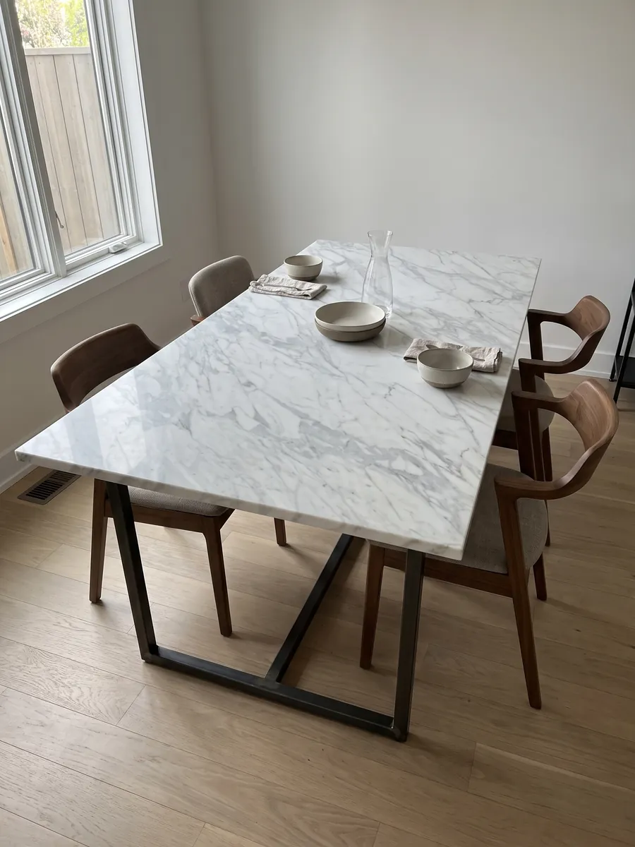 Dining table with a white Calacatta Classic marble top on a steel base: white with fine light gray veins running diagonally across the slab