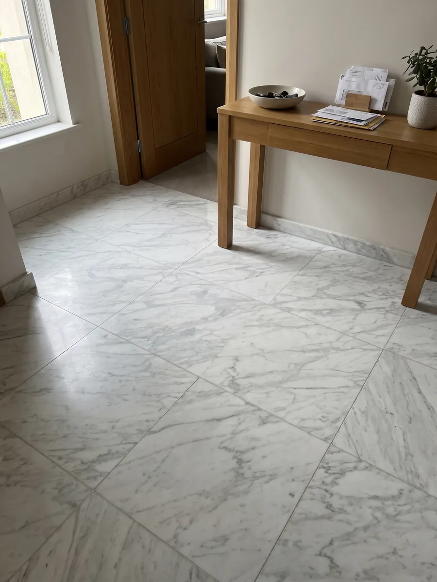 Entryway floor in large white Calacatta Classic marble slabs with natural light: white with fine light gray diagonal veins across the whole slab
