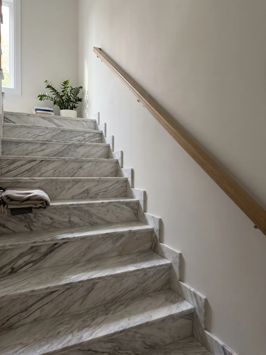 Interior staircase with white Calacatta Manhattan marble steps and a handrail: white with fine, soft gray veins that flow on the diagonal