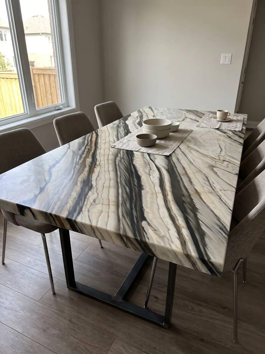 Dining table with a white Calacatta Oyster marble top on a steel base: wide black and brown bands running parallel in a diagonal over cream