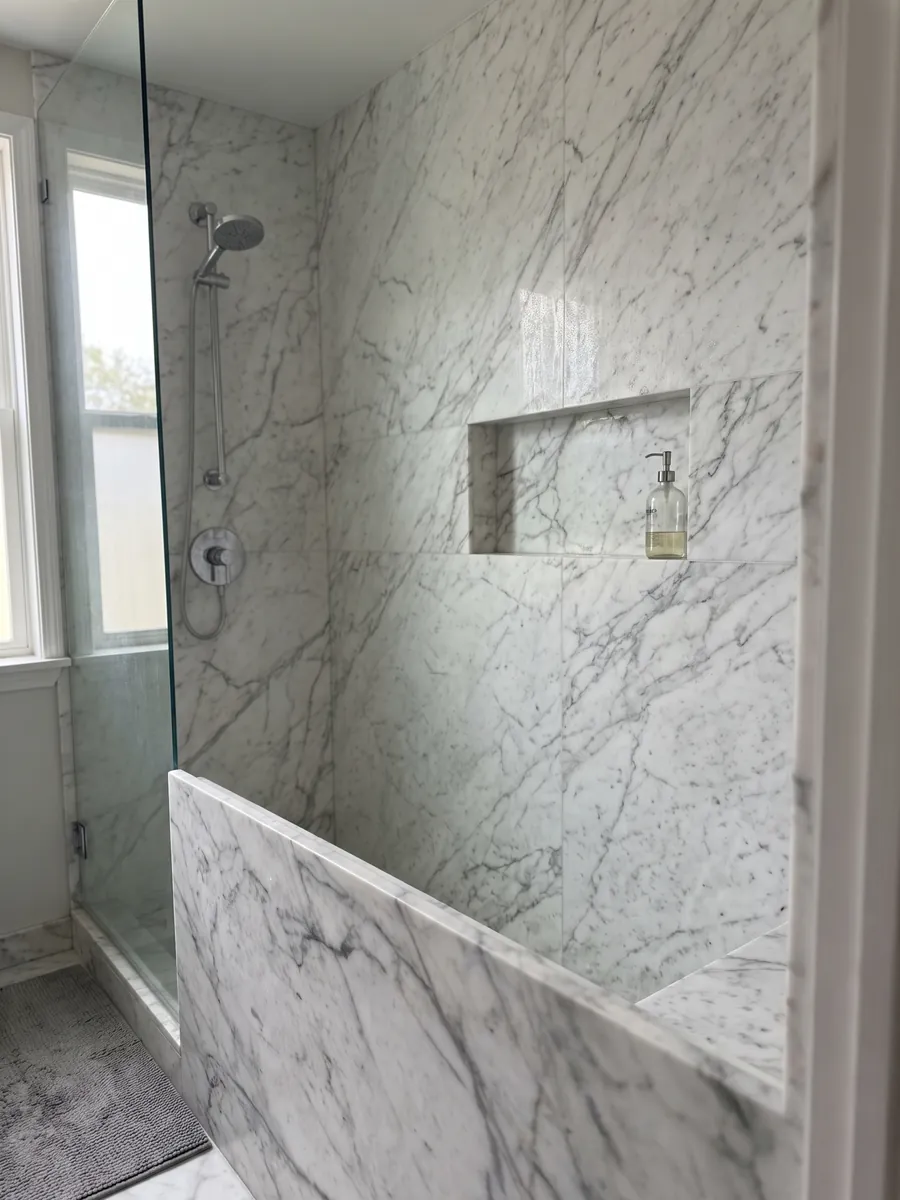 Shower clad in full slabs of white Calacatta Vagli marble with a recessed niche: white with fine gray veins in an irregular web