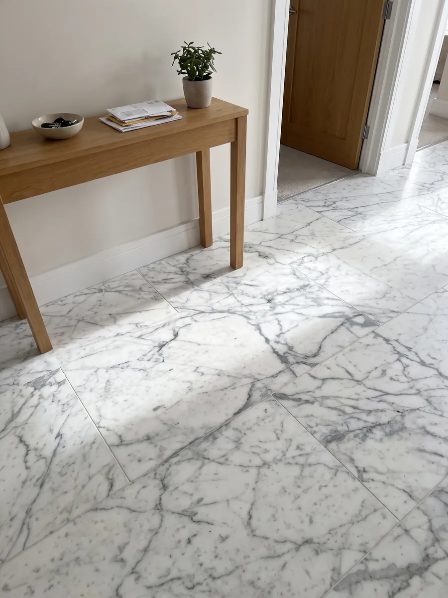 Entryway floor in large slabs of white Calacatta Vagli marble with natural light: white with fine gray veins in an irregular web