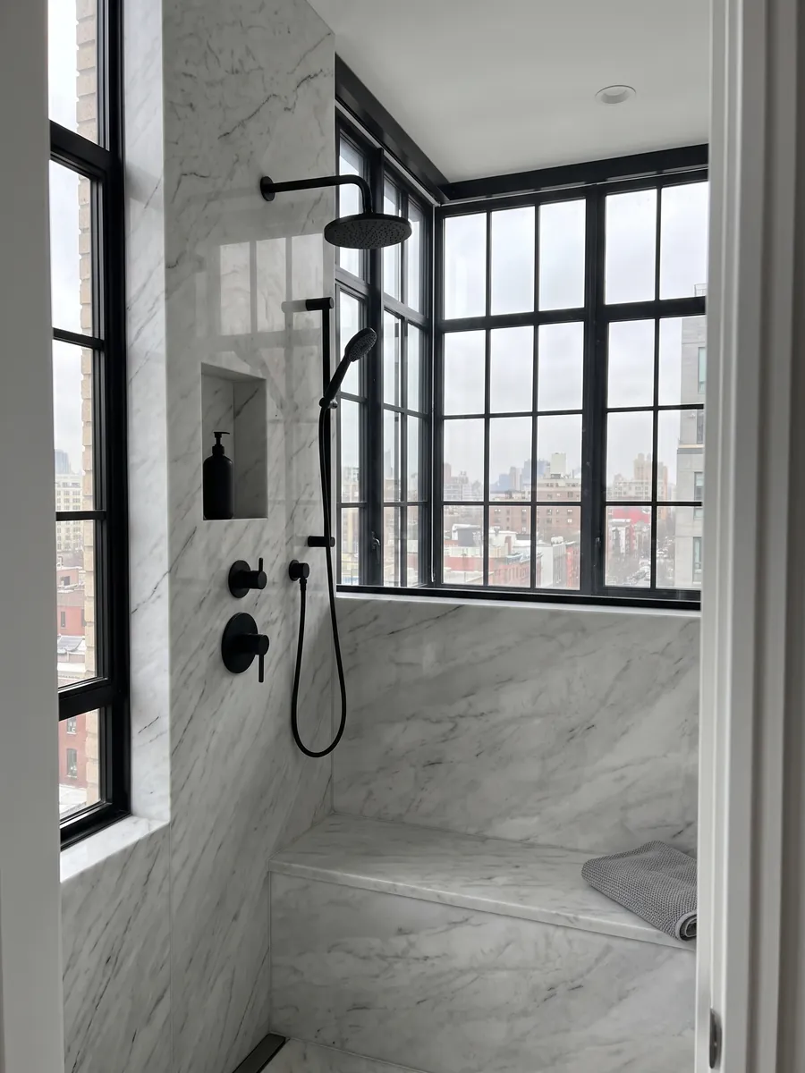 Shower clad in full slabs of white Dolomite marble with a recessed niche: grayish white with fine gray veins and the occasional darker line