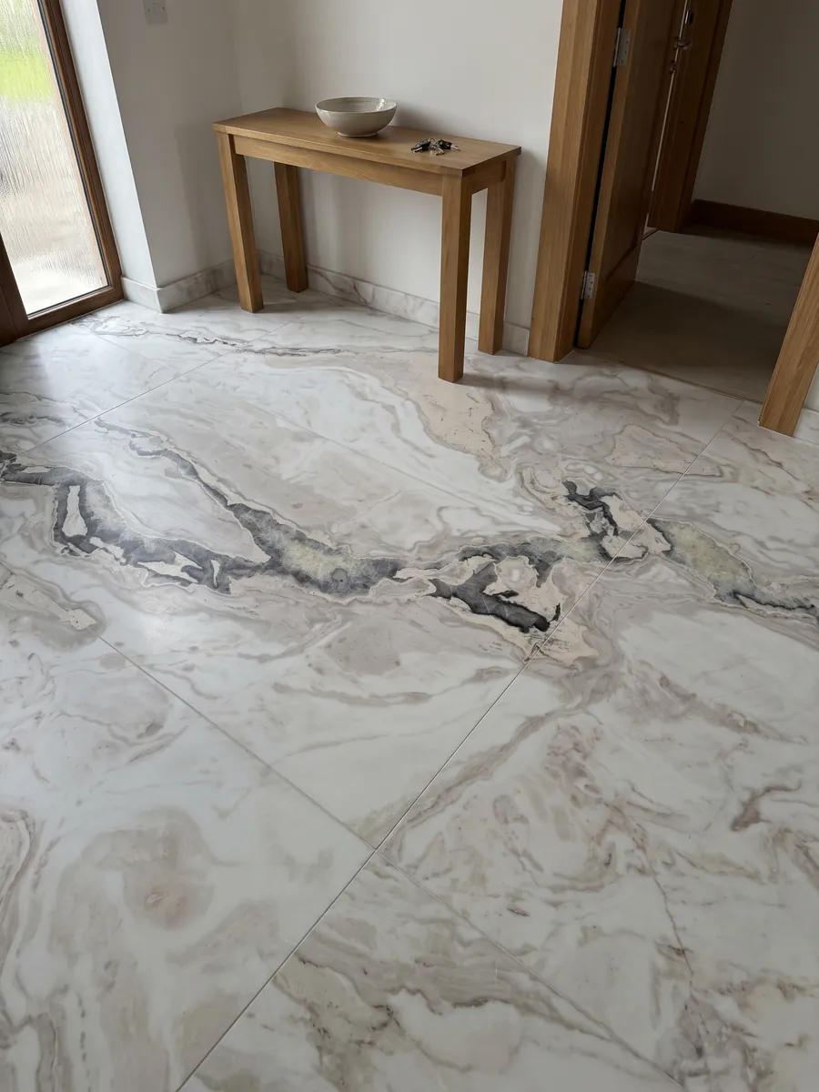 Entryway floor in large slabs of white Dover White marble with natural light: white with an irregular dark gray vein crossing the top