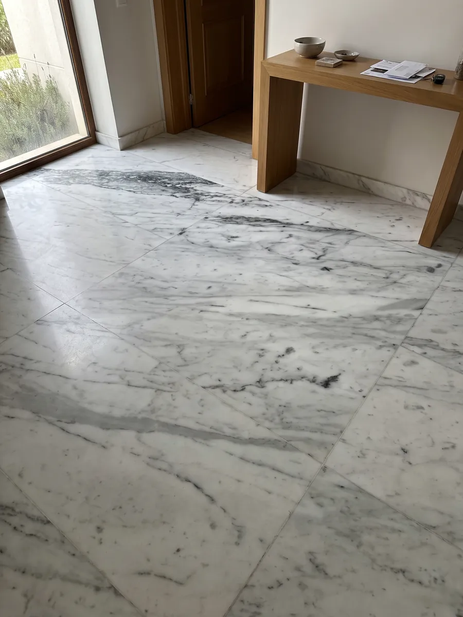 Entryway floor in large slabs of Bianco Gioia marble with natural light: white with diagonal gray veins, denser and darker toward the top