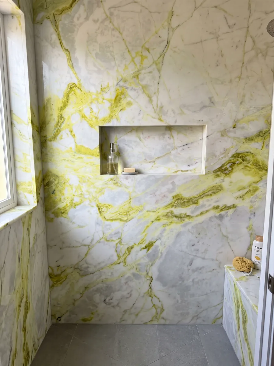 Shower clad in full slabs of white Luminous marble with a recessed niche: bluish white with very intense lemon yellow veins