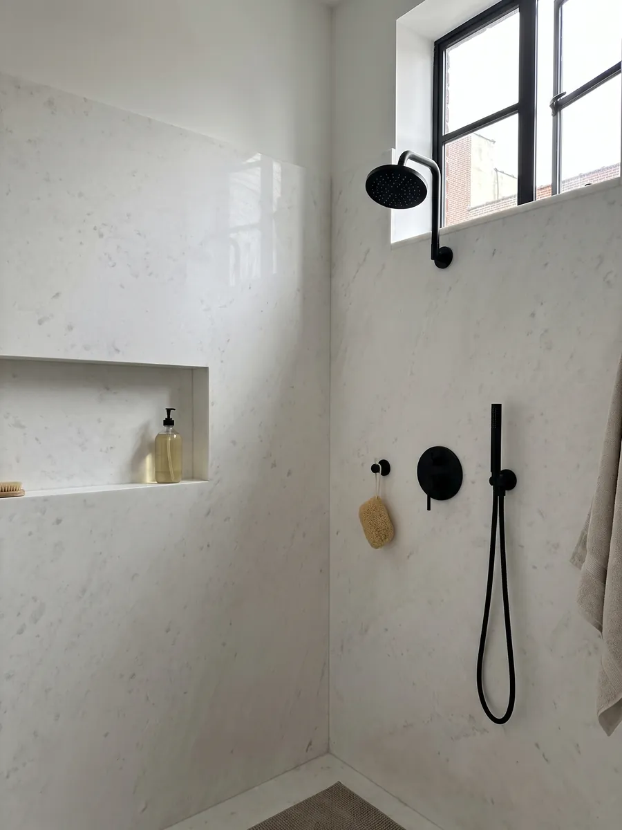 Shower clad in full Opal White marble slabs with a recessed niche: plain, uniform white with almost no pattern
