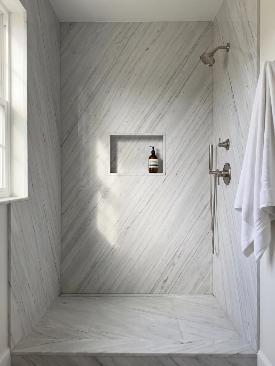 Shower clad in full slabs of white Palissandro marble with a recessed niche: grayish white with fine parallel gray strokes on the diagonal