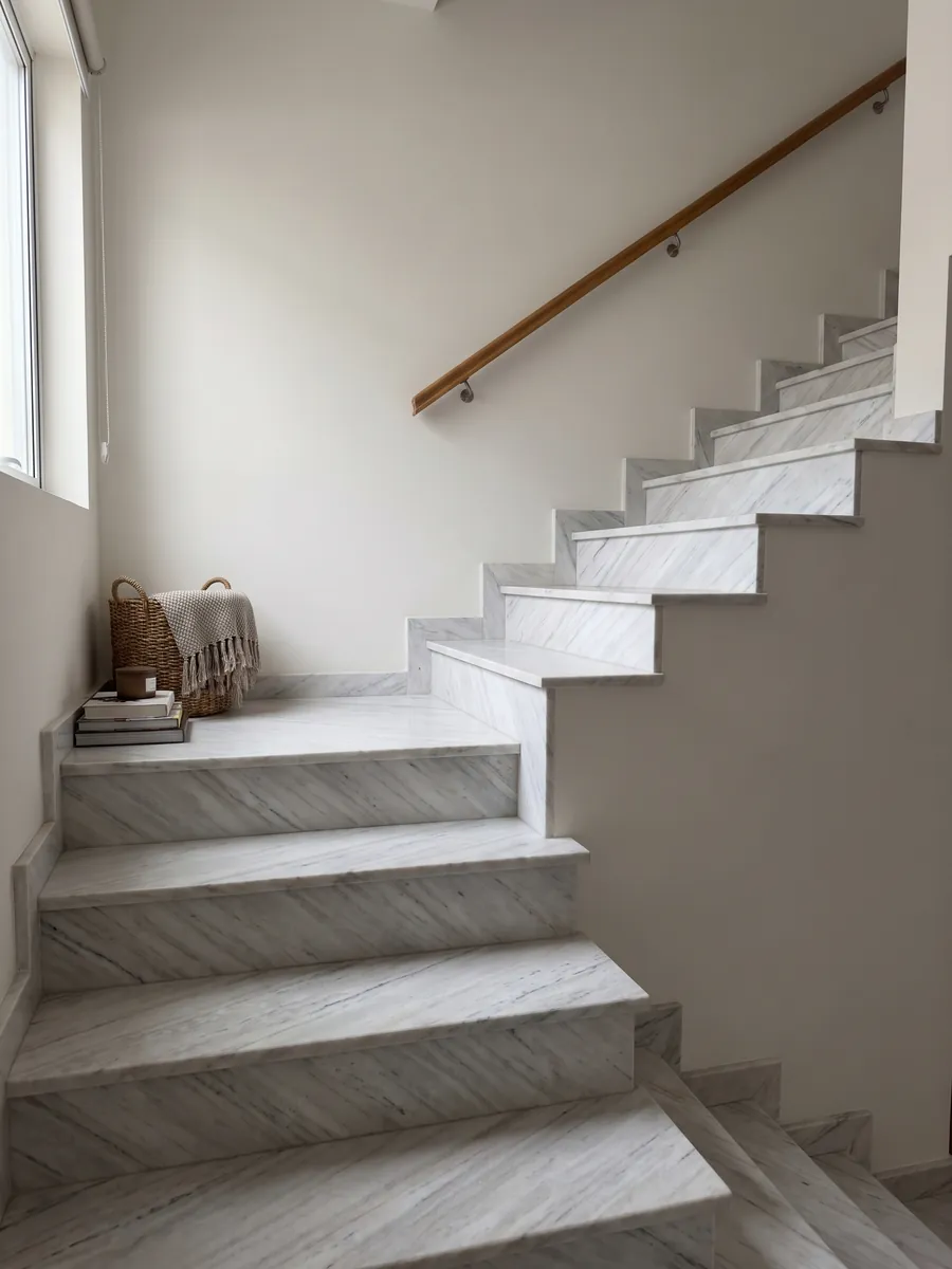 Interior staircase with white Palissandro marble treads and a handrail: grayish white with fine parallel gray strokes on the diagonal