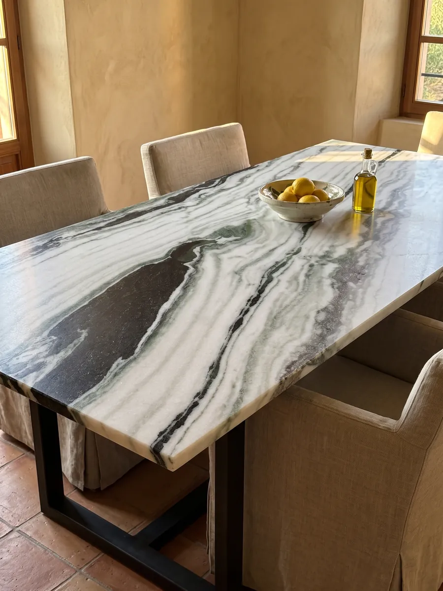Dining table with a white Panda White marble top on a steel base: white with thick diagonal black bands and green touches