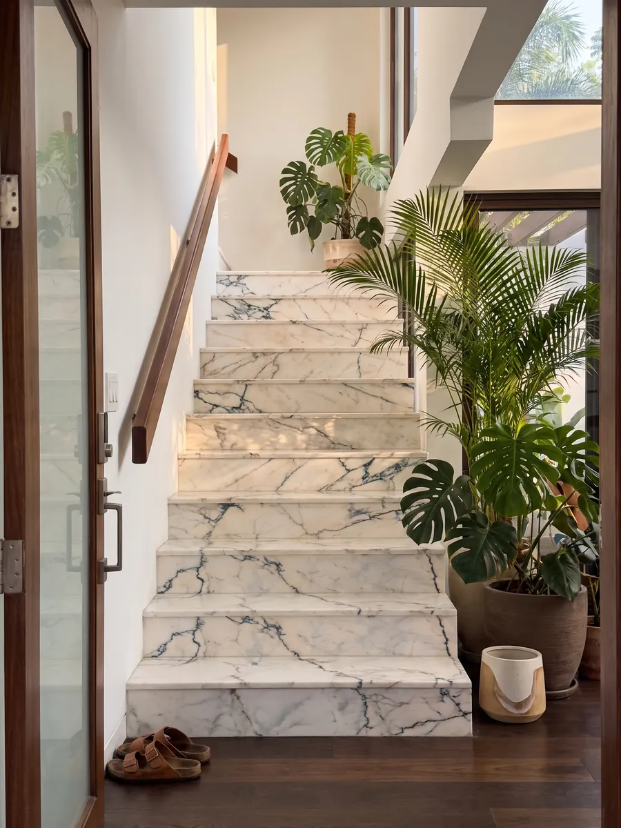 Interior staircase with white Paonazzo marble treads and a handrail: warm white with fine dark teal veins that look like cracks