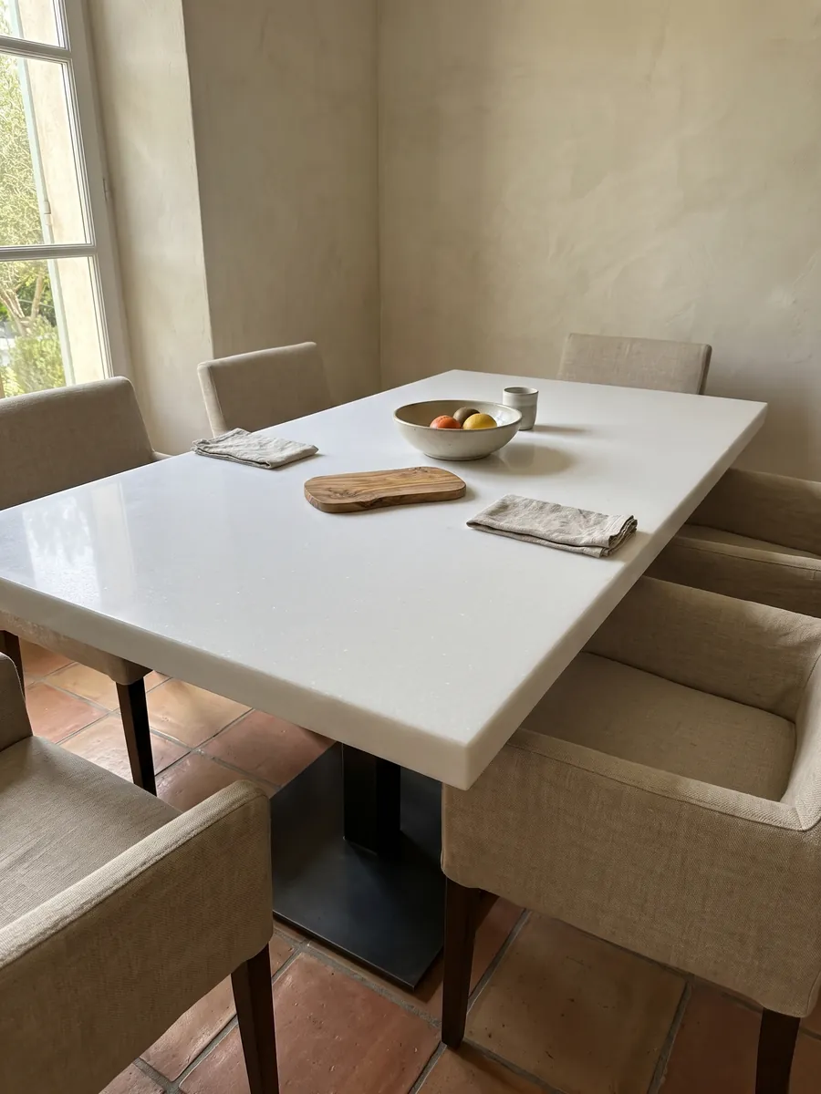 Dining table with a Pure White marble top on a steel base: uniform pure white, no visible veins or stains