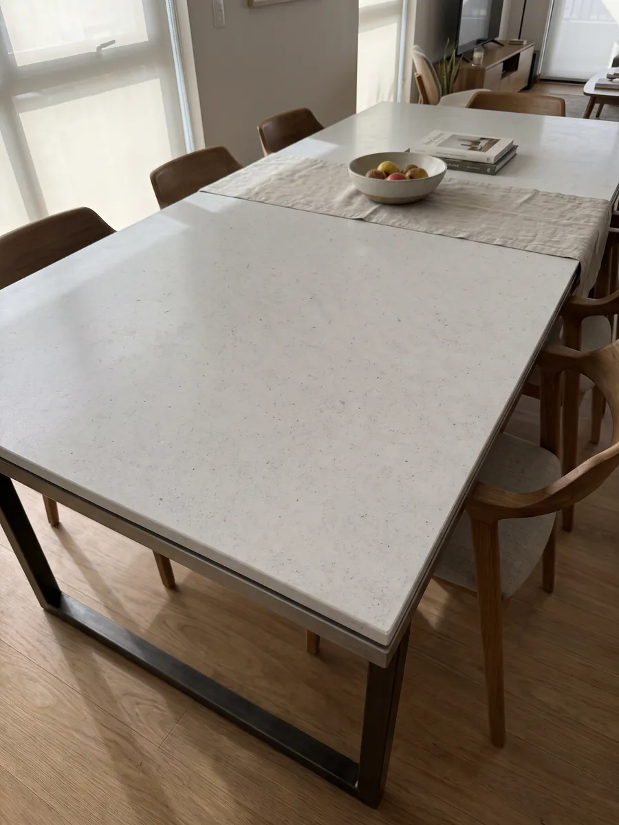 Dining table with a Bianco Siberia marble top on a steel base: plain grayish white with small scattered dark dots
