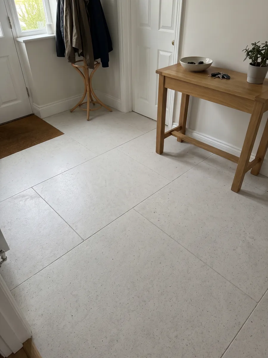 Entryway floor in large Bianco Siberia marble slabs with natural light: plain grayish white with small scattered dark dots