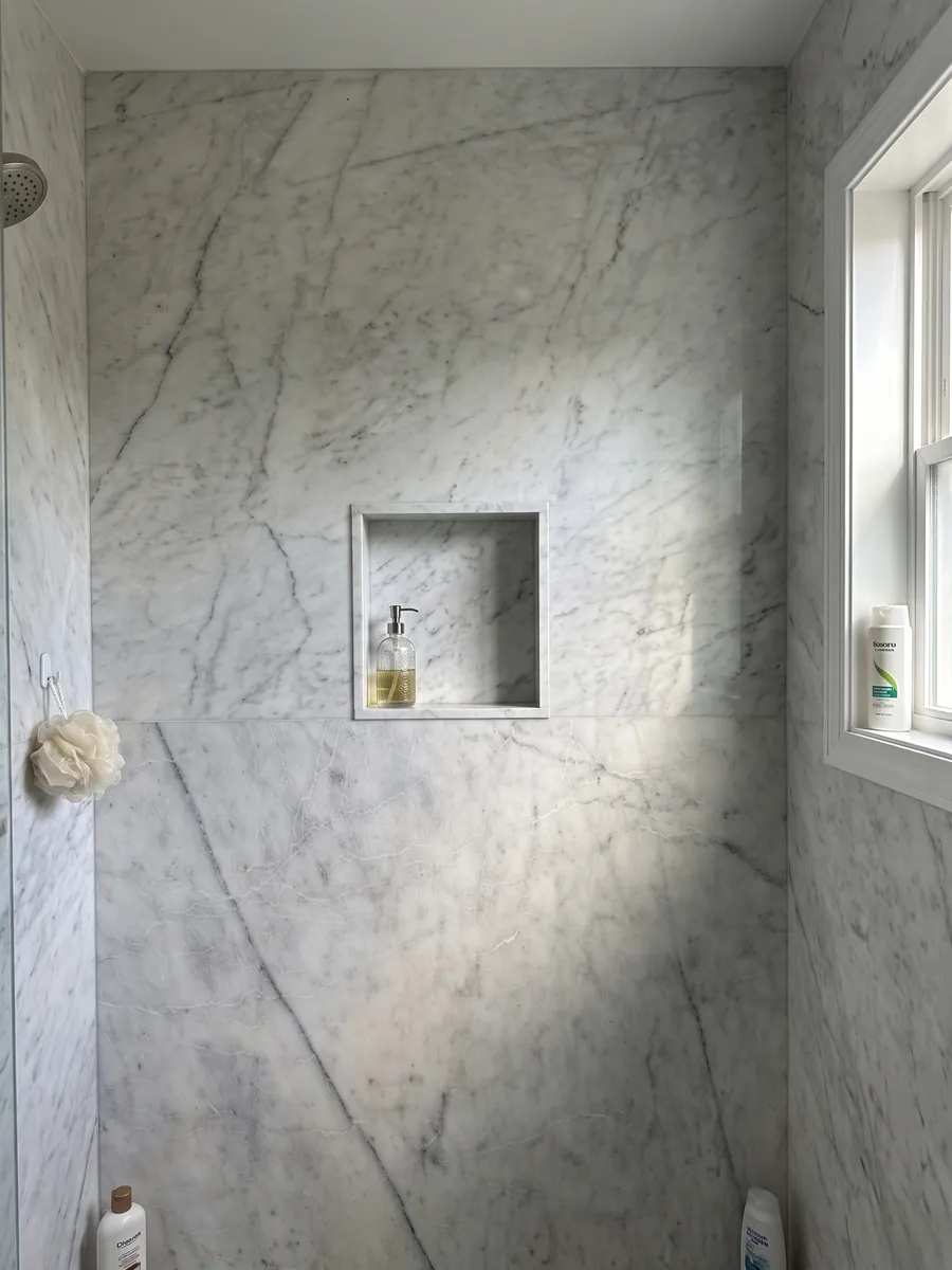 Shower clad in full Silver Glace white marble slabs with a recessed niche: clean white with a few fine gray veins running diagonally