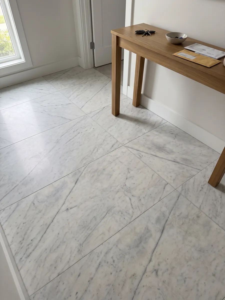 Entryway floor in large Silver Glace white marble slabs with natural light: clean white with a few fine gray veins running diagonally