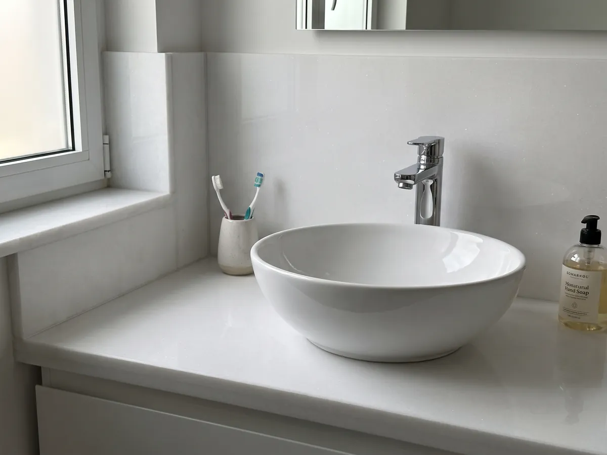 Vanity top and bathroom wall in white Thassos marble with a white sink and chrome fixtures: uniform pure white with no visible pattern