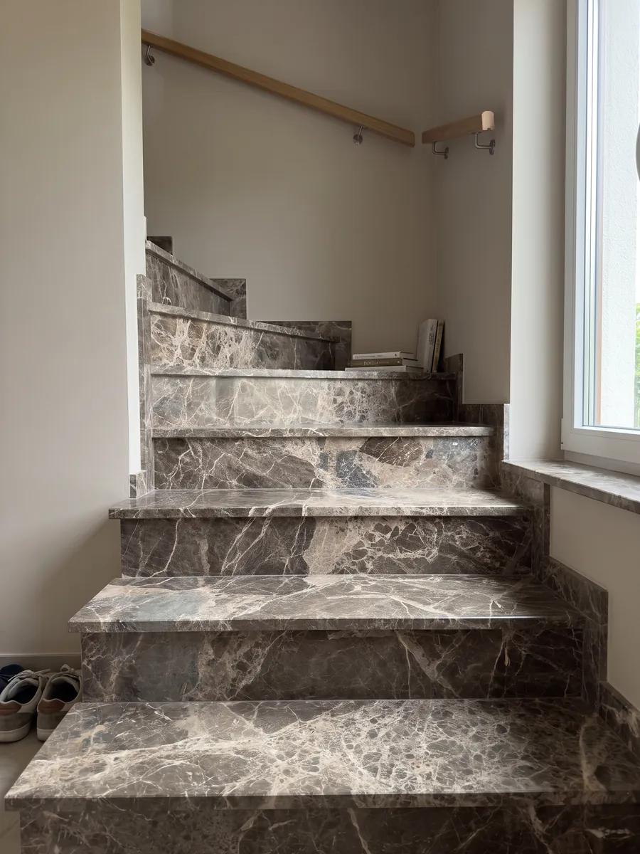 Interior staircase with brown Breccia Paradiso marble steps and a handrail: large gray-brown fragments joined by a network of light beige veins