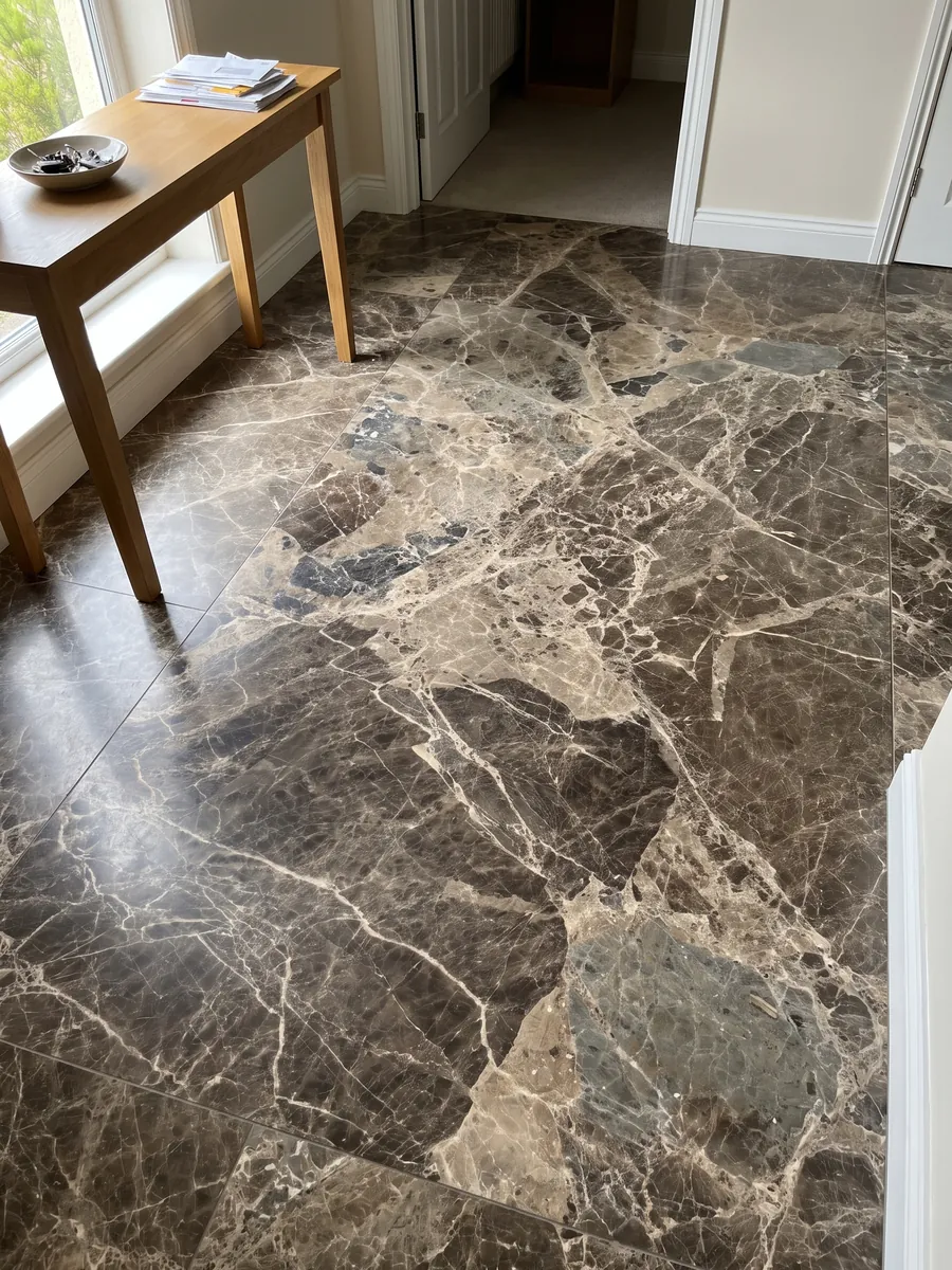 Entryway floor in large slabs of brown Breccia Paradiso marble with natural light: large gray-brown fragments joined by a network of light beige veins