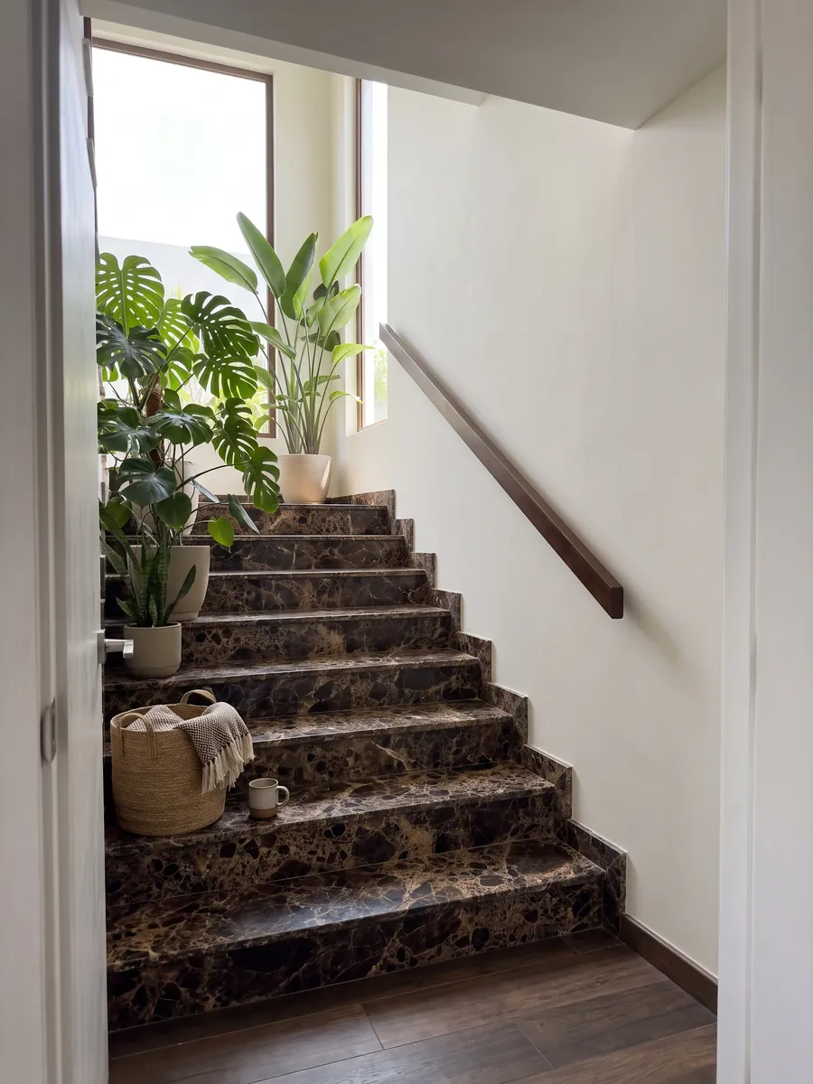 Interior staircase with Emperador Dark marble treads and a handrail: almost black dark brown patches joined by a dense beige web