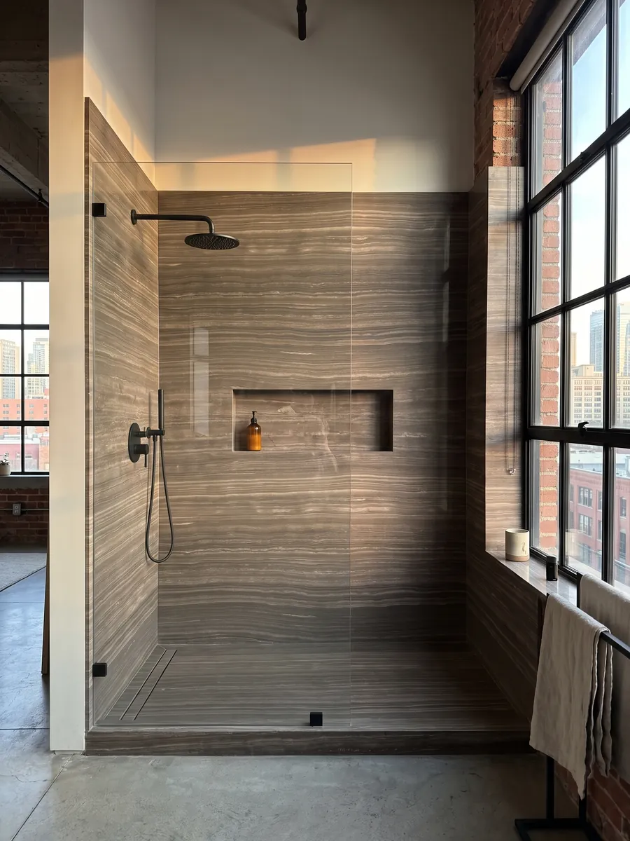 Shower clad in full slabs of brown Eramosa marble with a recessed niche: grayish brown with fine parallel horizontal wood-like lines