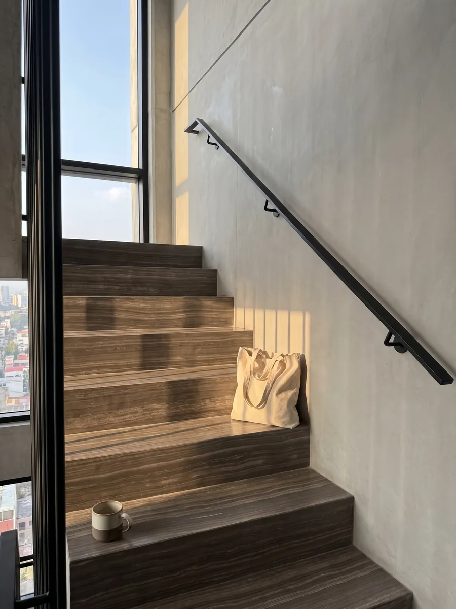 Interior staircase with brown Eramosa marble treads and a handrail: grayish brown with fine parallel horizontal wood-like lines
