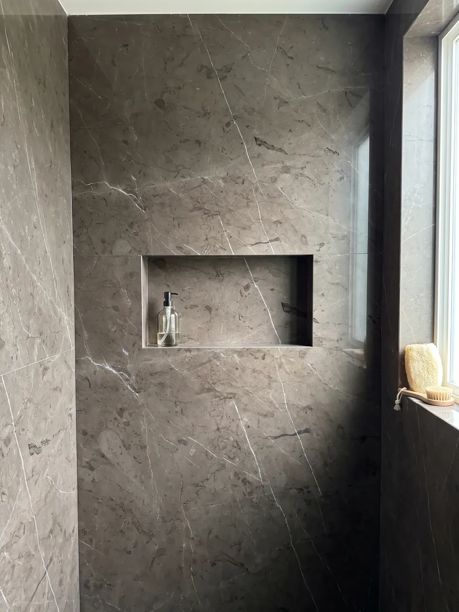 Shower clad in full brown Grafite marble slabs with a recessed niche: dark background between brown and graphite with a few very fine white veins