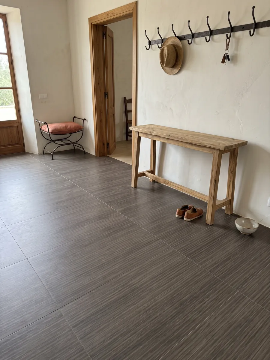 Entryway floor in large slabs of brown Venghé marble with natural light: fine, continuous horizontal lines that recall a dark wood