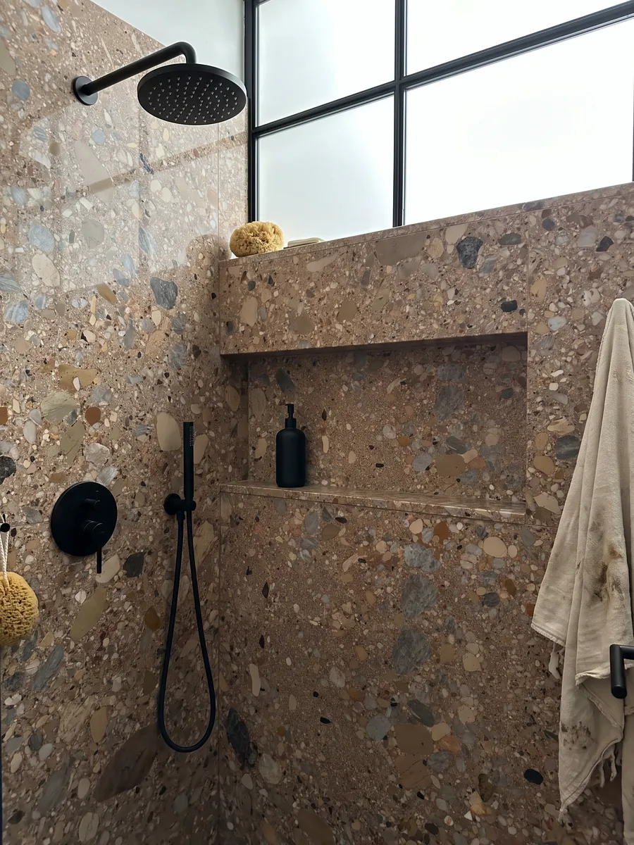 Shower clad in full slabs of Ceppo Rosso marble with a recessed niche: reddish brown matrix with gray and beige pebbles of various sizes