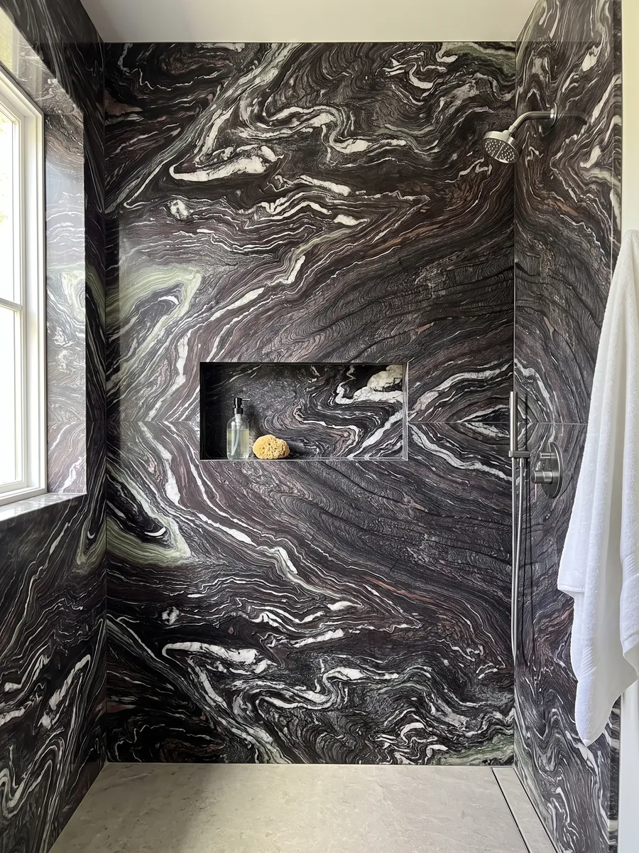 Shower clad in full Cipollino Ondulato marble slabs with a recessed niche: deep purple background with strongly wavy, folded white veins